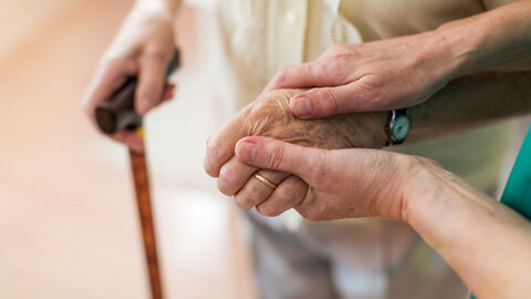 Krankenschwester tröstet ihre ältere Patientin, indem sie die Hände hält Krankenschwester tröstet ihre ältere Patientin, indem sie die Hände hält