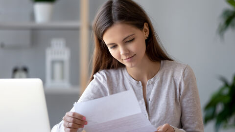 Lächelnde junge Frau, die einen Brief liest Lächelnde junge Frau, die einen Brief liest