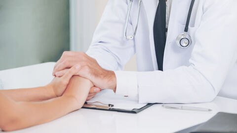 Arzt beruhigt Patientin durch Halten der Hände