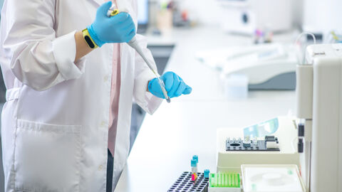 Person in blauen Handschuhen gießt Blutprobe ins Reagenzglas im Labor Person in blauen Handschuhen gießt Blutprobe ins Reagenzglas im Labor