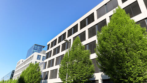 Bürogebäude mit vielen Fenstern und Bäumen davor