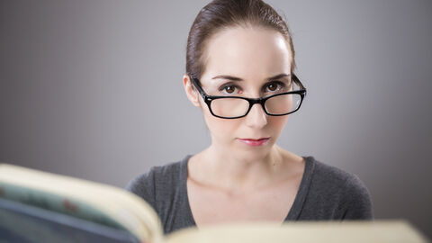 Junge Frau mit Brille liest ein Buch und lernt Junge Frau mit Brille liest ein Buch und lernt