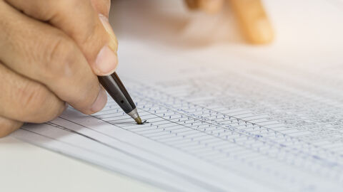 Hand mit Stift, die ein Dokument ausfüllt