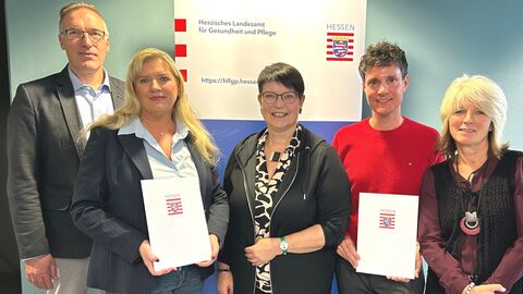 Zwei der vier Personen halten eine Urkunde in der Hand.